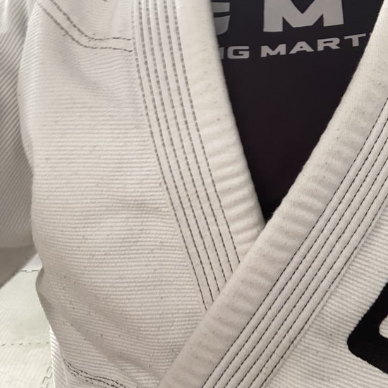 A speed up video of multiple pairs of adults wearing white BJJ gis branded with GMA wrestling on grey mats. 