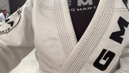 A speed up video of multiple pairs of adults wearing white BJJ gis branded with GMA wrestling on grey mats. 